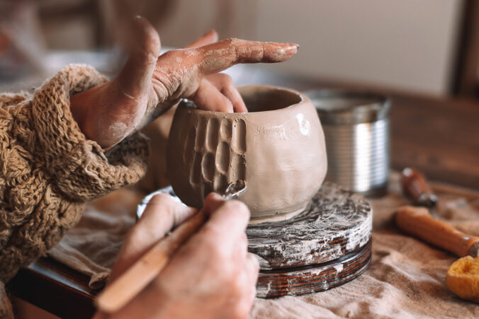 Female sculptor making clay mug in a home workshop,hands close up.Small business,entrepreneurship,hobby, leisure concept