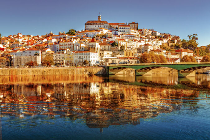 View of Coimbra from the left bank of the Mondego River. Reflection of the urban area and the University in the waters of the river.