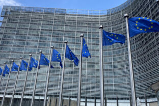 Blue with yellow stars, european flags fly outside the european headquarters berlaymont building in brussels, belgium.