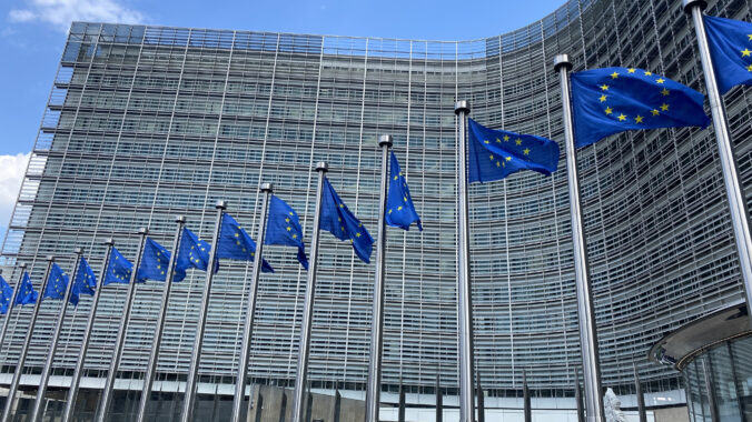 Blue with yellow stars, european flags fly outside the european headquarters berlaymont building in brussels, belgium.