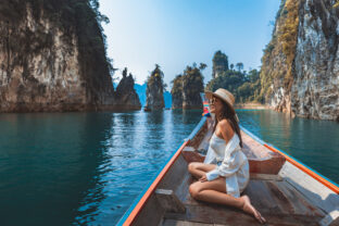 Traveler asian woman relax and travel on Thai longtail boat in Ratchaprapha Dam at Khao Sok National Park Surat Thani Thailand