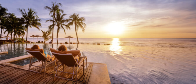 Beach holidays for couple in luxury hotel, banner background with copyspace, man and woman relaxing near swimming pool