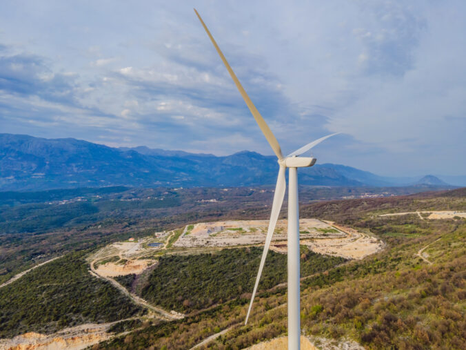 Wind turbines on beautiful sunny summer autumn mountain landsape. Curvy road through mountain Eolic park. Green ecological power energy generation. Wind farm eco field