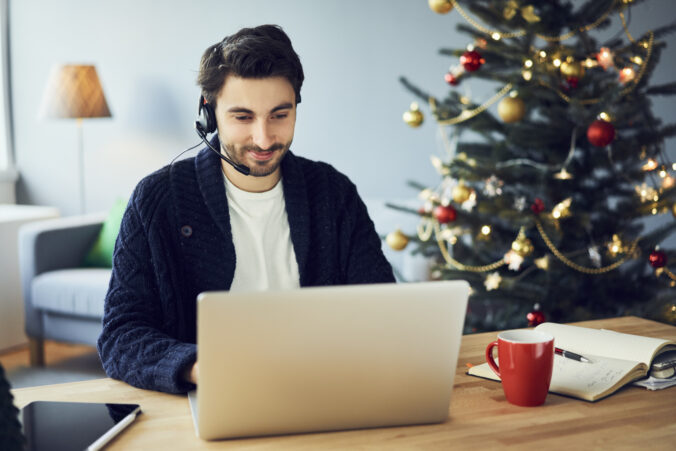 Young adult man with headset working from home during Christmas holidays