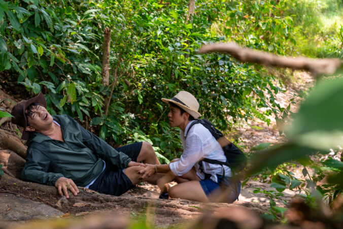 Asian mature injured on knee during hiking in forest.