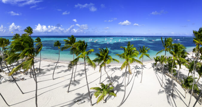 Aerial panorama of white sand Bavaro beach with green coconut palm trees and turquoise color of the Caribbean sea. Best destinations for vacations in Dominican Republic