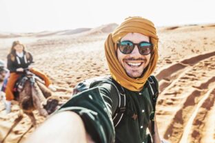 Čo nerobiť v Egypte ako turista? Turista na ťave s úsmevom v púšti počas slnečného dňa v Egypte.