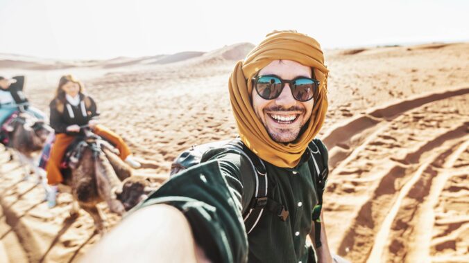 Čo nerobiť v Egypte ako turista? Turista na ťave s úsmevom v púšti počas slnečného dňa v Egypte.