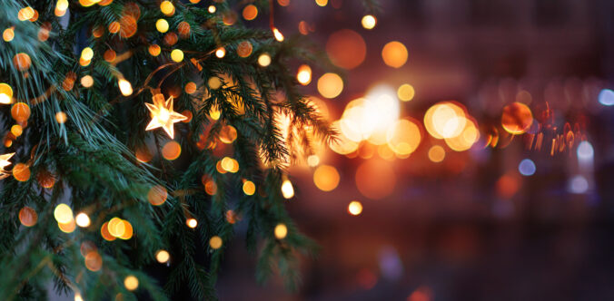 Christmas tree with garland lights. Evening city with blurred background