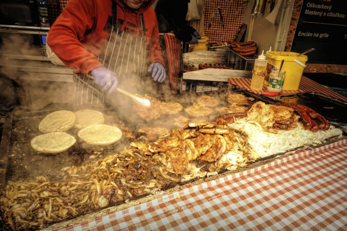 Closeup on people preparing a typical Slovakian Burger with onions and mustard on Christmas market