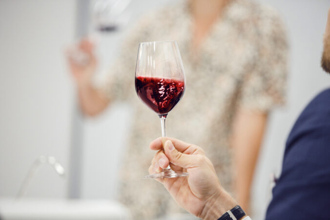 Sommelier looking at holding red wine glass, analysis it color, scrutiny taste and tartness of alcoholic drink, faceless pov shot. Man takes part in lecture on production and history of wine origin.