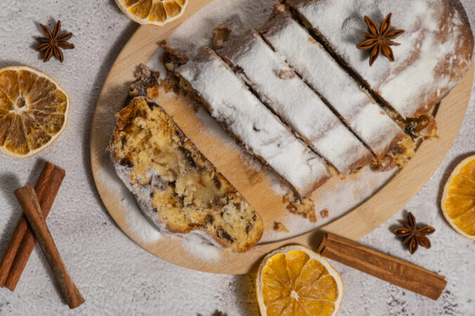 Slices of Homemade Christmas traditional cake pie with marzipan nuts and dried fruits pastry dessert stollen. Winter holidays season atmosphere. Delicious tasty composition home table setting