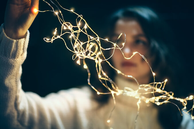 Beautiful young woman hanging christmas lights