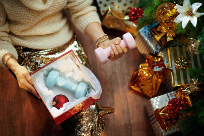 Housewife holding christmas present box and dumbbells