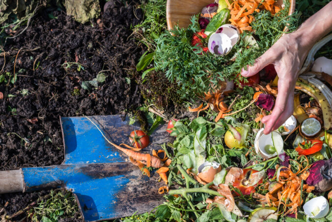 Compost box outdoors full with garden browns and greens and food wastes, woman throwing away wastes