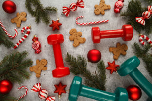 Christmas flat lay composition with gym dumbbells, gingerbread man cookies and decorations.