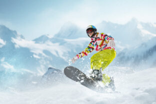 Young girl in sportswear sliding on snowboard over snowy mountains background. Winter activity