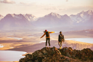 Young couple is standing at mountain top with great view