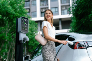 Young woman travel with EV electric car in green sustainable city innards