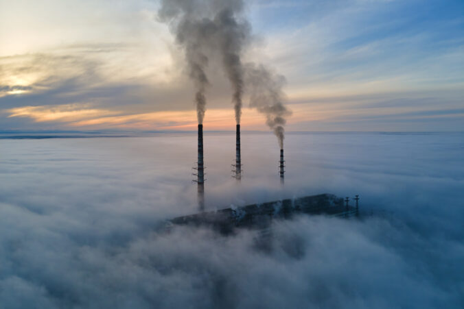 Coal power plant high pipes with black smoke moving upwards polluting atmosphere. Production of electrical energy with fossil fuel concept