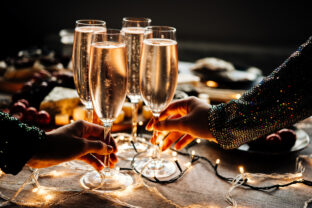 Friends celebrating Christmas or New Year eve party with champagne or sparkling wine.