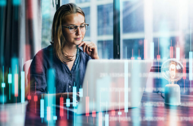 Businesswoman working at modern office.Technical price graph and indicator, red and green candlestick chart and stock trading computer screen background. Double exposure. Trader analyzing data