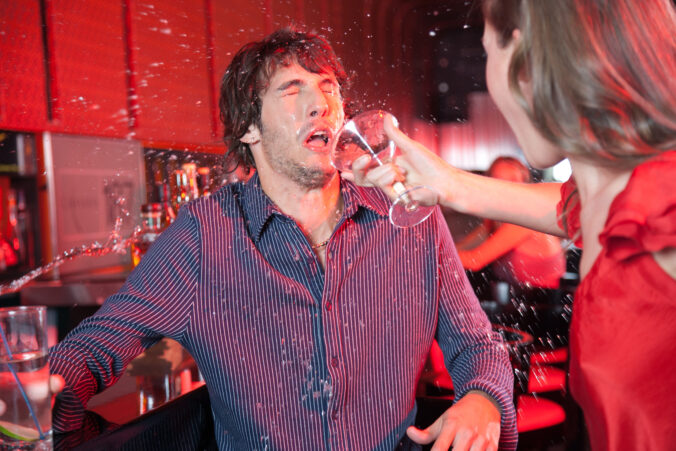 Woman in nightclub throwing beverage in man&#039;s face