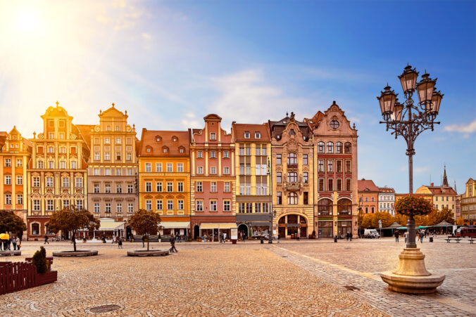 Central market square in Wroclaw Poland with old colourful houses, street lantern lamp and walking tourists people at gorgeous stunning morning sunrise sunshine. Travel vacation concept