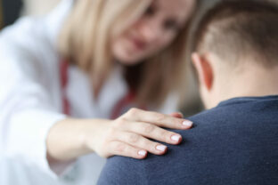 Female doctor holding shoulder of male patient closeup