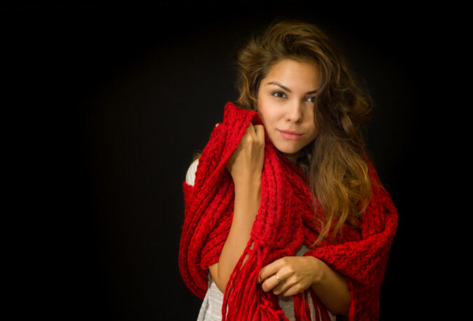 Portrait of beautiful young girl with red comforter