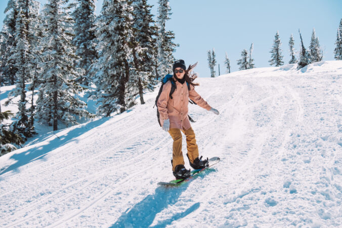 Young girl snowboarder with a snowboard on the nature among the mountains in sunny weather