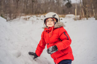 Cute boy climbs on a snowy mountain