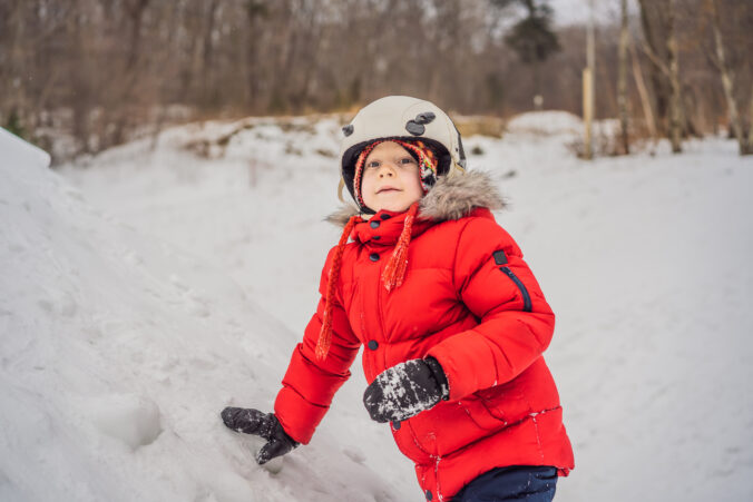 Cute boy climbs on a snowy mountain