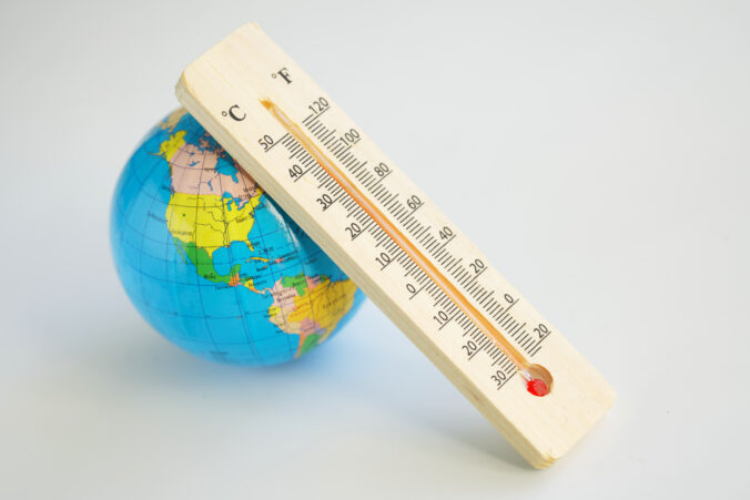 Globe and wooden eco friendly thermometer on a white background. Temperature in Celsius and Faradays. Concept of climate change and global warming. Copy space. Selective focus.