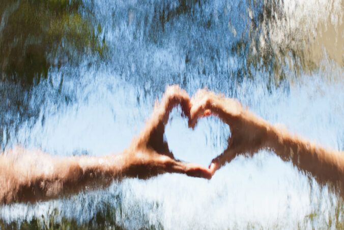 Hands making heart shape behind glass