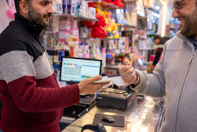 A man makes contactless payments at a bookshop or gift shop using his smartwatch, seamlessly utilizing NFC or WiFi technology, without the need for physical touch