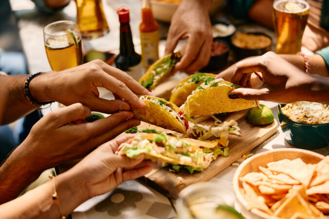 Close up of friends eating tacos in Mexican restaurant.