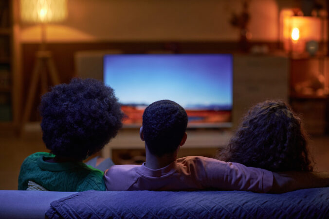 Back view of three people watching TV