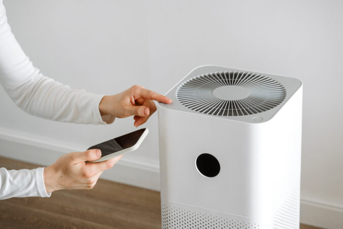 Woman use smartphone with app for air purificator and ultrasonic humidifier control