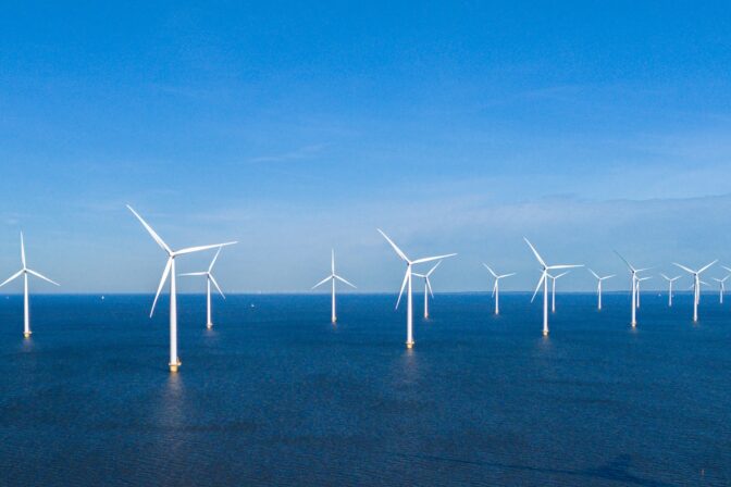 Offshore veterné elektrárne na mori počas slnečného dňa s modrou oblohou.