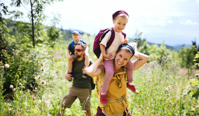 Family with small children hiking outdoors in summer nature.