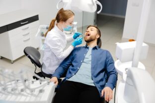 Ako má prebiehať dentálna hygiena? Muž na dentálnej hygiene v zubnej ambulancii. Dentálna hygienička vykonáva profesionálne čistenie zubov.