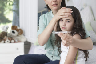 Woman in bedroom taking young girls temperature