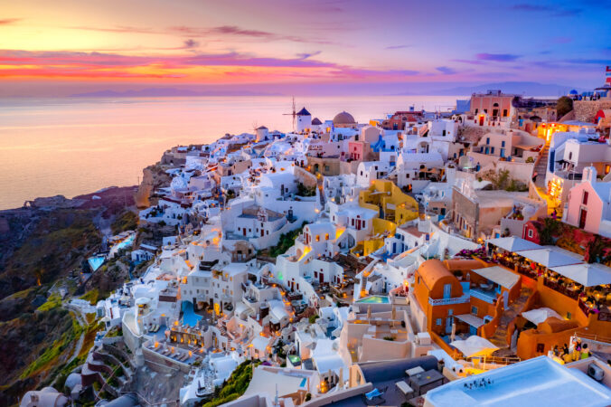 Mesto Oia na ostrove Santorini, Grécko. Tradičné a slávne domy a kostoly s modrými kupolami nad kalderou.
