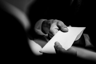 Businessman giving bribe money in the envelope to partner