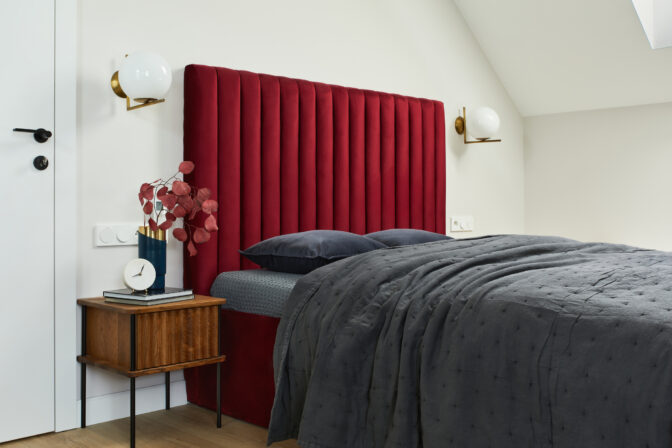 Minimalistic elegant bedroom interior with red bed, grey bedclothes and wooden furniture. Glamour style inspiration. Template.