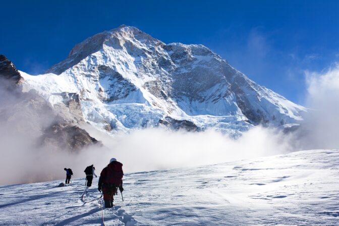 Group of climbers on rope on glacier and Mount Makalu