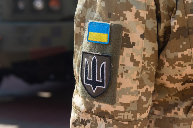 Military badge of ukrainian army with trident and yellow blue flag on the uniform of a Ukrainian soldier