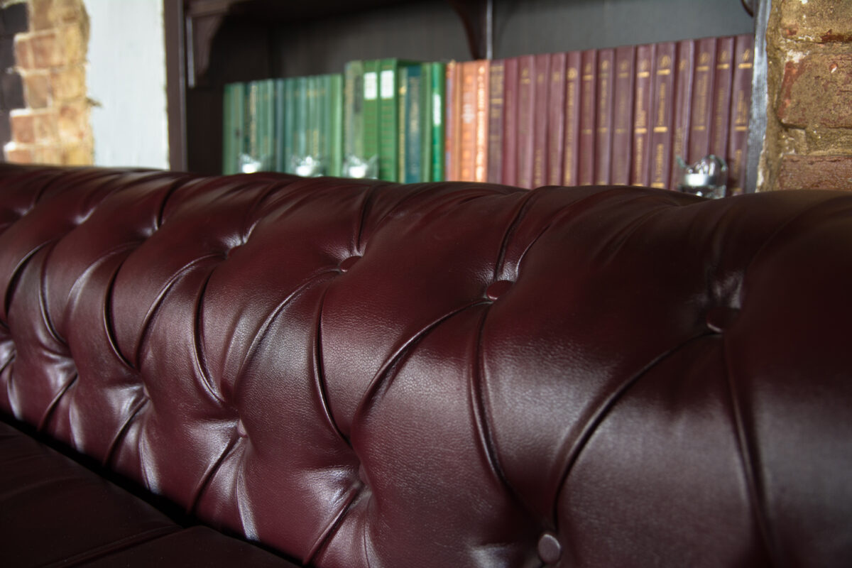 Background close up burgundy leather sofa and bookshelf