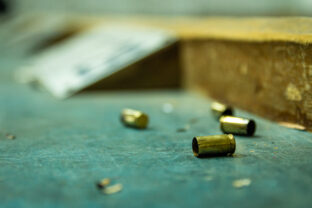 Empty pistol bullet shells on wooden table in a shooting range